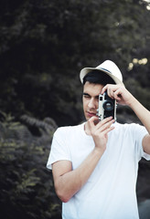 Young man with retro camera taking photos in nature