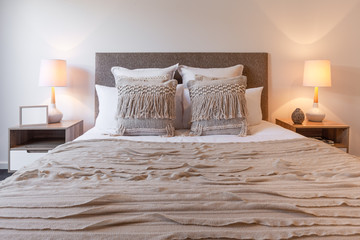 Decorative pillows on bed arrangement with bedroom lamps and bedside tables