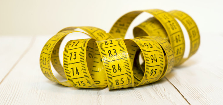 Measuring weight concept - yellow tape measure banner close-up