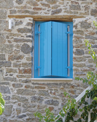 Fototapeta na wymiar vibrant blue shutters window on stone wall