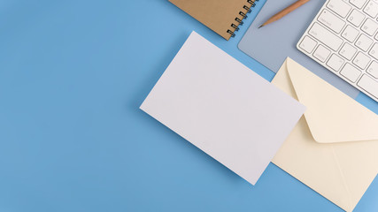 Flat lay, top view office table desk. Workspace with blank note book, keyboard, office supplies and coffee cup on light blue background.