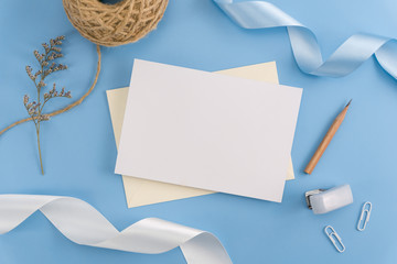 A wedding mock up concept. Wedding Invitation, envelopes, cards Papers on light blue background with ribbon and decoration. Top view, flat lay, copy space