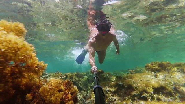 Man shooting underwater video about himself by his action camera