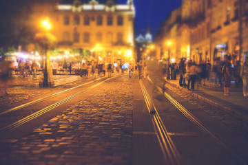 A crowd of people moving on the old european city night street defocused blurred abstract image