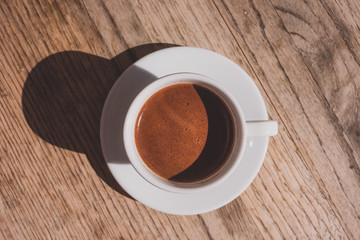 Cup of coffee on wooden table, top view