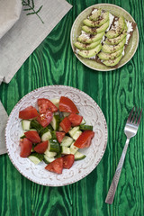 A healthy salad of fresh tomatoes and vegetables and a homemade soft cheese sandwich, avocados and seasoning on toast of hard wheat. A healthy breakfast.