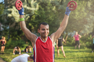 Young athlete performs exercises with dumbbells in the fresh air.