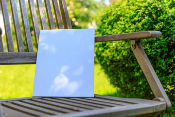 Mockup of a magazine cover on a wooden chair in the garden in summer