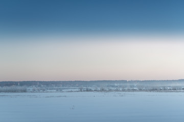 Beautiful winter landscape at sunset with fog and snow