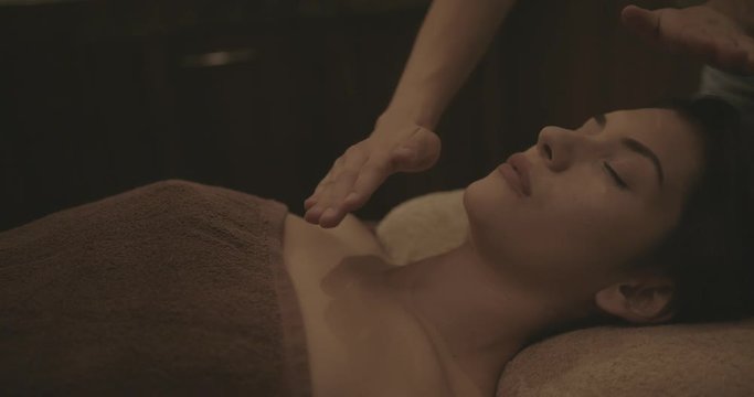 Woman doing reiki alternative medicine treatment at holistic therapy spa
