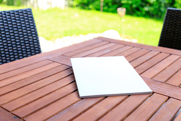 Mockup of a magazine cover on a wooden table in the garden in summer