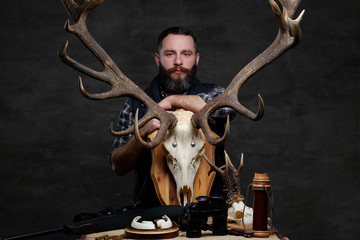 Bearded hunter in a fleece shirt and hat with his trophies.