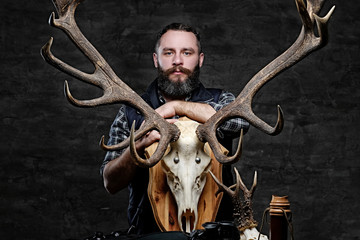 Bearded hunter in a fleece shirt and hat with his trophies.