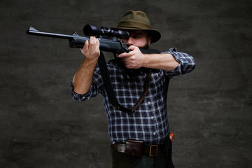Hunter aiming a rifle in sight while preparing to make an accurate shot at the prey.
