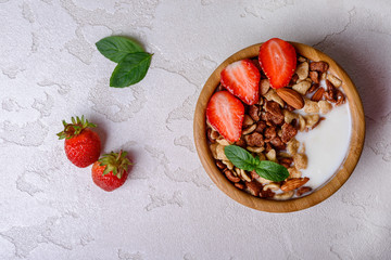 Healthy breakfast  with muesli,  berries and nuts  in bowl on grey background. Healthy food concept. Flat lay.