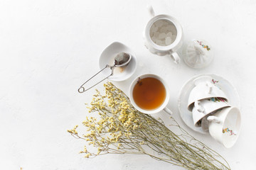 Tea in a Cup with dry flowers on a white table. Copy space text