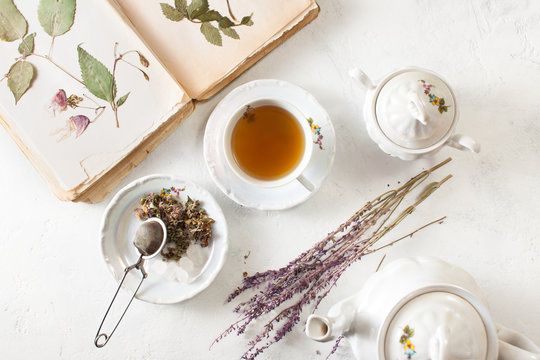 A Cup of tea and a book with a herbarium on a white table
