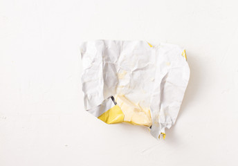 A piece of butter in an open wrapper on white.