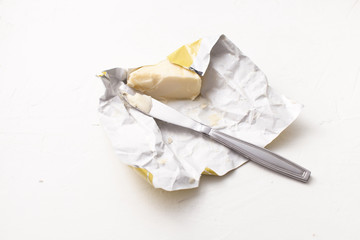 A piece of butter in an open wrapper on white.