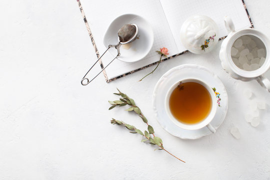 Tea in a Cup with dry flowers on a white table. Copy space text
