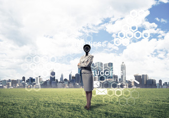 Camera headed woman standing on green grass against modern citys