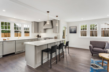 Kitchen in New Luxury Home with Hardwood Floors, and Pendant Lights in New Luxury Home. Has Stainless Steel Appliances and Partial View of Living Room.