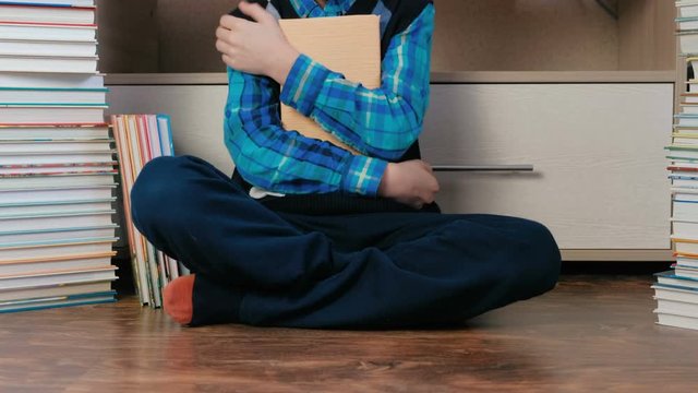 Unrecognizable seven-year-old boy sitting among books.