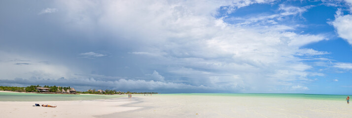 HOLBOX, MEXICO - MAY 22, 2018: Panaoramic view of tourists walking the beach at Holbox Island while a storm passes through