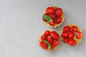 Sweet Dessert Tartlets with Strawberries and Cream Isoalted over Gray Textured Background. Summer Sweet Cakes.