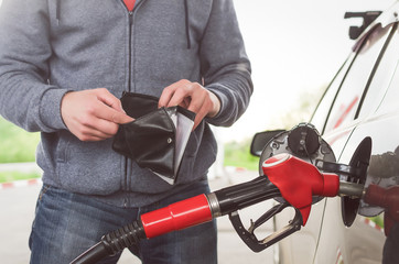 Lack of money for gasoline and fuel. Expensive gasoline. Driver man holds one dollar end empty...