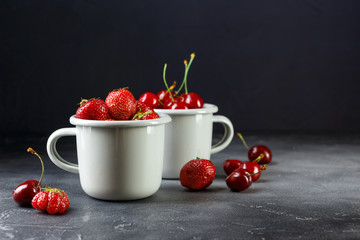 Fresh strawberries and sweet cherry in enameled cups