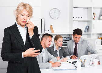 Crying woman at office on background with coworkers