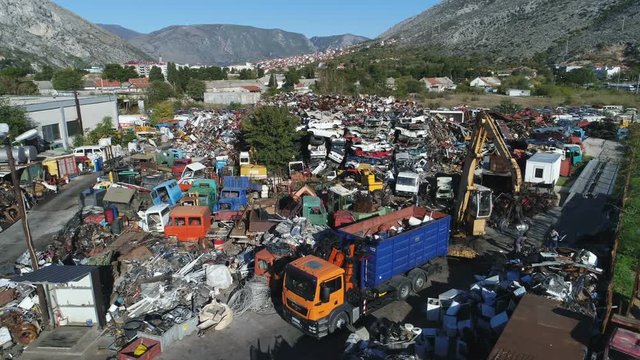 Drone flight over colorful scrapyard of rusty vehicles and other material that can be recycled, in Bosnia and Herzegovina