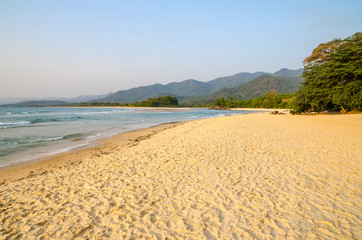 Beautiful Bureh Beach in the afternoon with yellow sand, green trees, sea and mountains, Sierra Leone, Africa