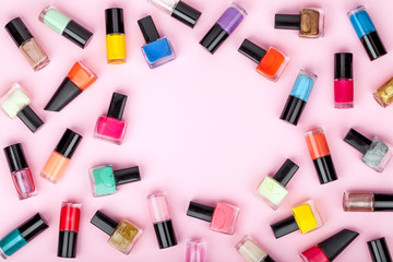 bottles of colorful nail polish on pink background. beauty and fashion trendy concept. flat lay, top view