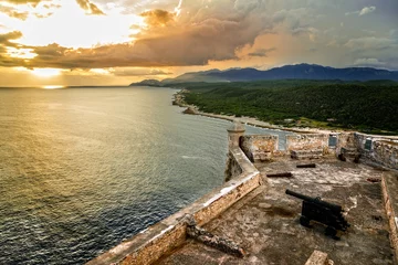 Papier Peint photo autocollant Travaux détablissement Murs du fort de San Pedro de La Roca avec canon, vue sur le coucher du soleil sur la mer des Caraïbes, Santiago de Cuba, Cuba
