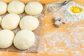 Baking background top view. Making sweet bun or bread dough. Cooking ingredients for pastry on wooden board with dough, egg, yeast, milk, flour. Culinary classes or recipe concept.