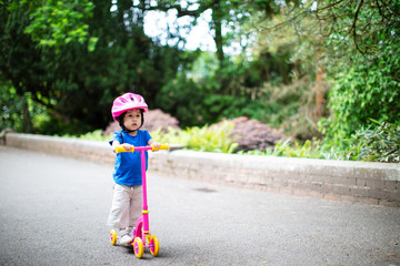 Fototapeta premium baby girl play balance scooter at summer park