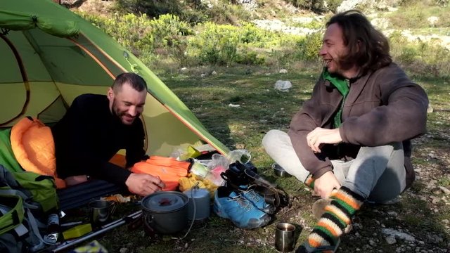 Friends travel and camping together and cooking breakfast near the tent in wild nature