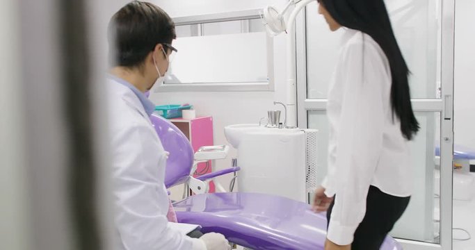 Young asian female patient talking with caucasian dentist in professional laboratory.