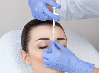 Naklejka premium The doctor cosmetologist makes the Rejuvenating facial injections procedure for tightening and smoothing wrinkles on the face skin of a beautiful, young woman in a beauty salon.Cosmetology skin care.