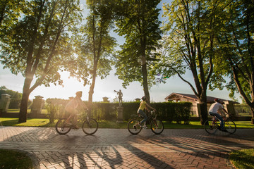 Fototapeta na wymiar Students spending time together in summer park. Young people cycling during beautiful sunny day. Friendship and active rest.