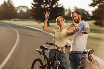 Happy couple of cyclists having fun outdoors. Cute people in love posing with bicycles on road. Love, romance, fun and healthy lifestyle concept.