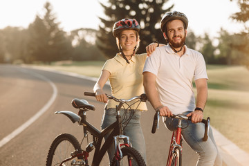 Obraz premium Happy carefree couple with bicycles outdoors. Happy couple standing with bicycles on the road and looking at camera. Healthy lifestyle concept.