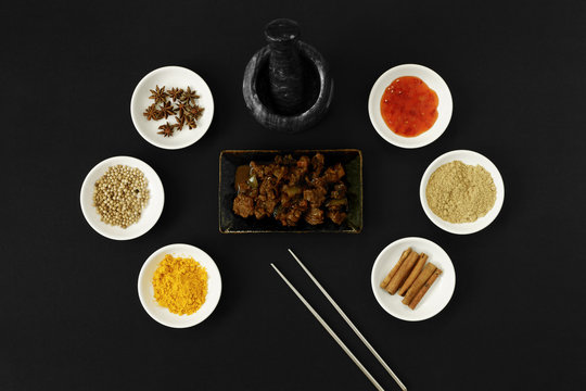 Beef dendeng cuisine with asian spices, herbs and cooking ingredients on black background.