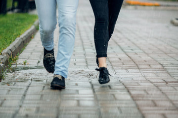 Young couple walking in the rain on puddles
