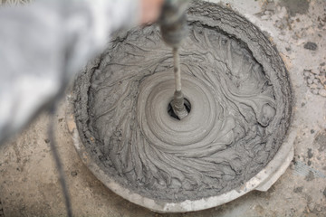 Builder mixing plaster in a bucket using an electric mixer