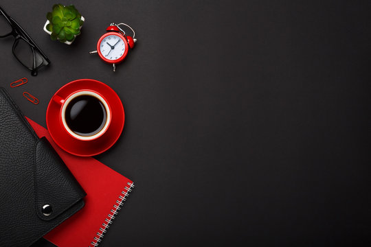 black background red coffee cup note pad alarm clock flower diary glasses empty place desktop