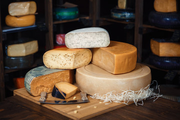 Cheese heads with slices and knives on a wooden board with an interior