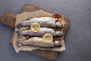 Fried trout with lemon and spices. Delicious and healthy lunch. Gray background, free space for text. Copy space.